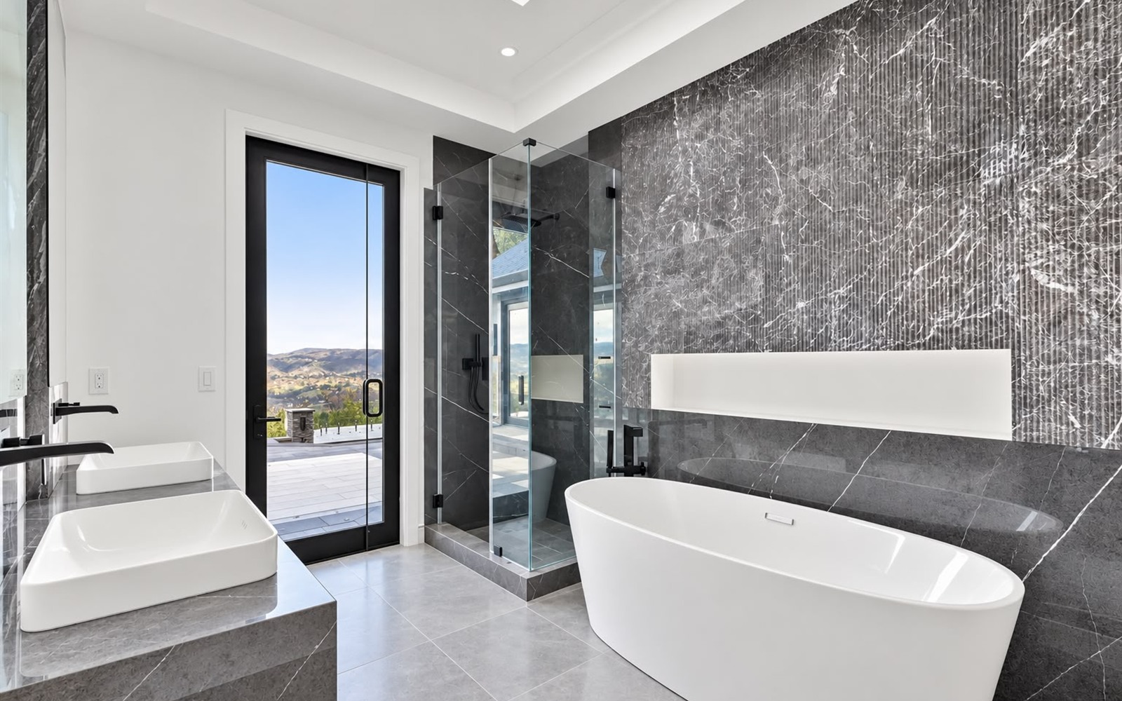 Finished bathroom with glass shower, double vanity, and freestanding tub by Prime Time Plumbing