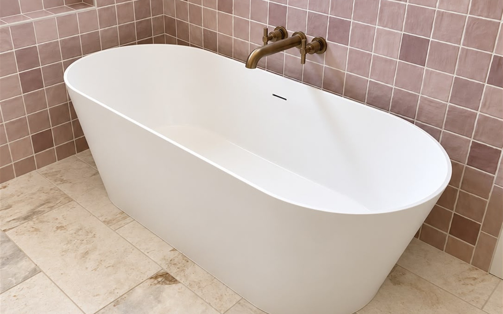 Finished bathroom with white freestanding soaking tub, brushed-brass wall filler, and handmade tile